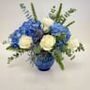 A sophisticated blend of vibrant blue hydrangeas, creamy white roses, and striking