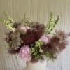 Soft blush peonies and tall white snapdragon spikes mingle with airy burgundy