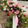A soft pastel memorial arrangement mounted on a white wooden cross designed