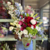 A dramatic red-and-white focal bloom with pink calla lilies and pale blue