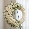 A luminous circular wreath of white blooms designed for sympathy and memorial