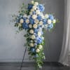 A serene blue-and-white standing spray shaped like a cross, designed for sympathy