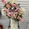 Pink roses and lilies arranged in a white floral cross