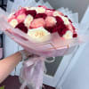 Bouquet of pink, white, and burgundy roses wrapped in pale pink paper