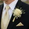 A cream rose boutonniere that reads timeless and refined-perfect for a wedding