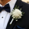 A single white rose boutonniere crafted for a refined wedding or black‑tie