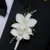 Two white dendrobium orchid blooms form a refined, ceremonial boutonniere that elevates