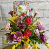 Mixed bouquet of pink, yellow, and purple flowers in a floral vase