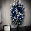 Blue and white funeral standing spray with a black ribbon