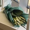 Bouquet of white calla lilies wrapped in teal paper