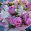 A lush swirl of large pink peonies and white tulips announces itself