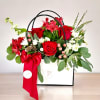 Red roses and white flowers in a white gift box with a red ribbon