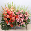 Large rectangular arrangement of peach gladiolus, orange dahlias, and pink roses in a low wooden container
