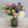 This sweet arrangement showcases a mix of ranunculus, tulips, spray roses and