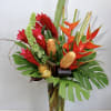 Tropical bouquet with red and orange flowers in a tall glass vase