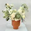 White floral arrangement in a terracotta vase with a green succulent