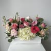 Mixed pink and white flowers arranged in a white wooden box