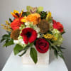 Mixed bouquet with red, orange, and yellow flowers in a white box