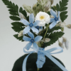 Small boutonniere with blue and white flowers and a light blue ribbon