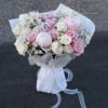 Bouquet of pink and white roses with baby's breath, wrapped in white paper and ribbon