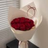 Bouquet of red roses wrapped in cream paper with a ribbon
