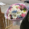 Pink and white mixed bouquet with blue filler flowers wrapped in pink paper