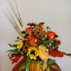 Ceramic pumpkin, daisies, sunflowers, roses, and alstroemeria with dry wheat making this