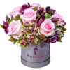 Pink roses and purple flowers arranged in a gray hat box