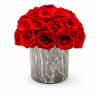 Compact arrangement of red roses in a gray marble-patterned cylinder vase