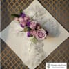 Lavender roses and purple flowers arranged on white lace ribbon