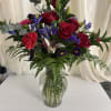 Deep red roses and upright lily buds create a striking centerpiece in