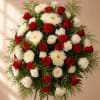 A dense, rounded standing spray built from red roses, white chrysanthemums, and