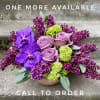Purple orchids and lavender roses in a low bowl arrangement