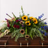 Sunflowers anchored at the center give this large casket spray a warm