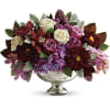 Mixed bouquet of roses and purple flowers in a silver pedestal vase