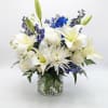 Pure white lilies and roses rise from a cloud of blue delphinium