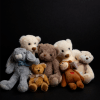 Assorted teddy bears and plush animals posed against a black background