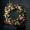 A lush garden-inspired wreath featuring roses, lilies, and seasonal blooms in soft
