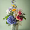 A colorful mix of hydrangea, roses, daisies, seasonal blooms, and fresh greenery
