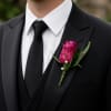 A timeless purple boutonniere featuring a fresh bloom accented with complementary greenery.