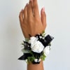 A sophisticated wrist corsage featuring fresh white spray roses, elegant black ribbon