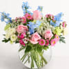 A charming mix of soft pink, blue, white, and green blooms designed