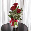 Red roses arranged in a clear glass vase with a red ribbon