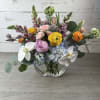 This arrangement has a lush, garden-inspired feel with peonies, orchids, ranunculus, hydrangea
