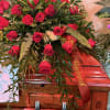 Red rose arrangement on a wooden casket with a red ribbon
