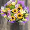 A vibrant mixed bouquet featuring cheerful sunflowers, elegant white lilies, soft lavender