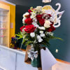 Red and white roses arranged in a glass vase with a silver bow