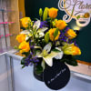 Yellow roses and white lilies arranged in a black box