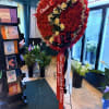 A timeless heart-shaped standing spray featuring rich red carnations, elegant white roses
