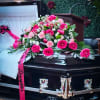 Pink rose and carnation casket spray with ribbon on a black casket